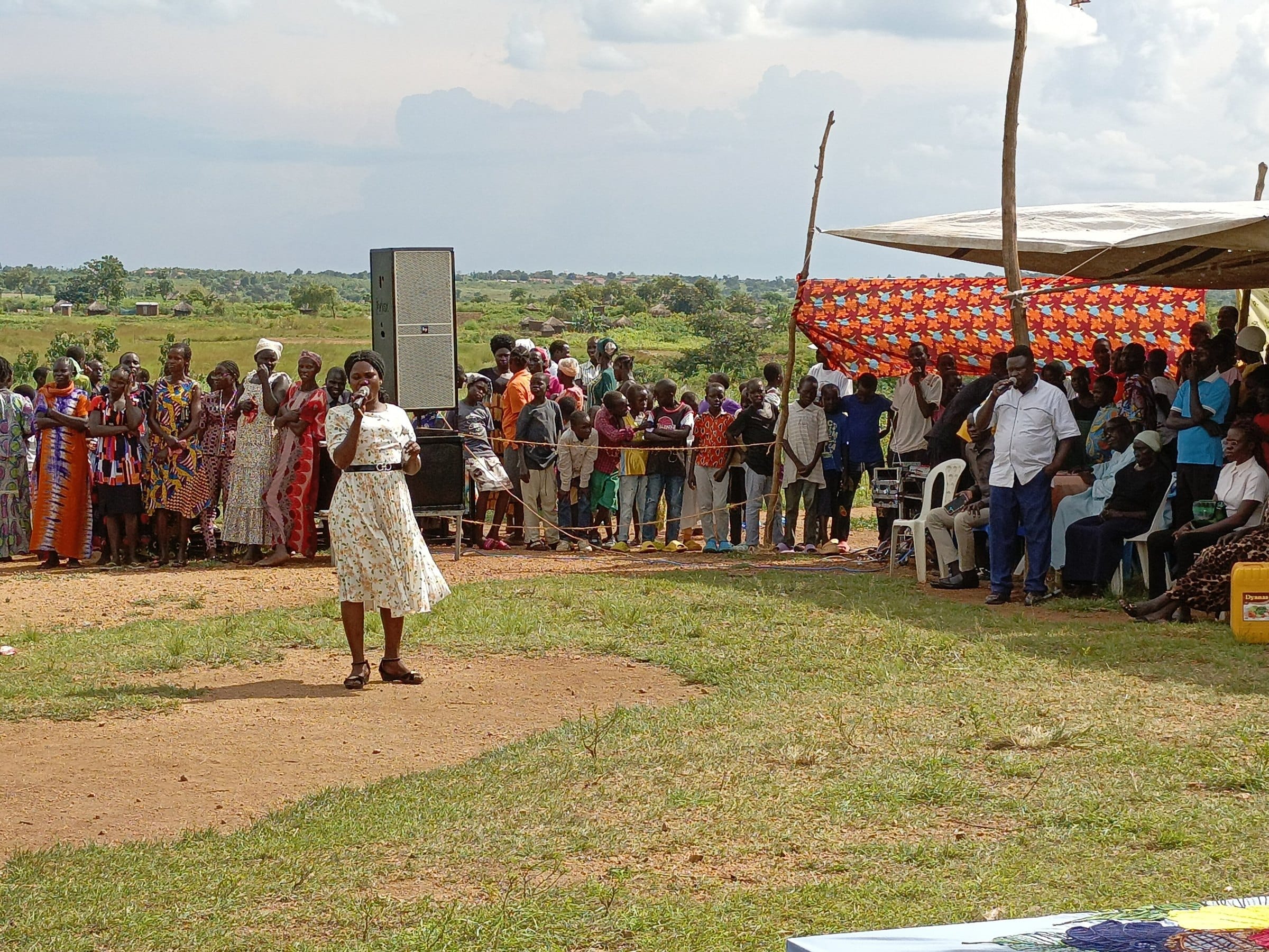 A woman addresses a large community gathering outdoors