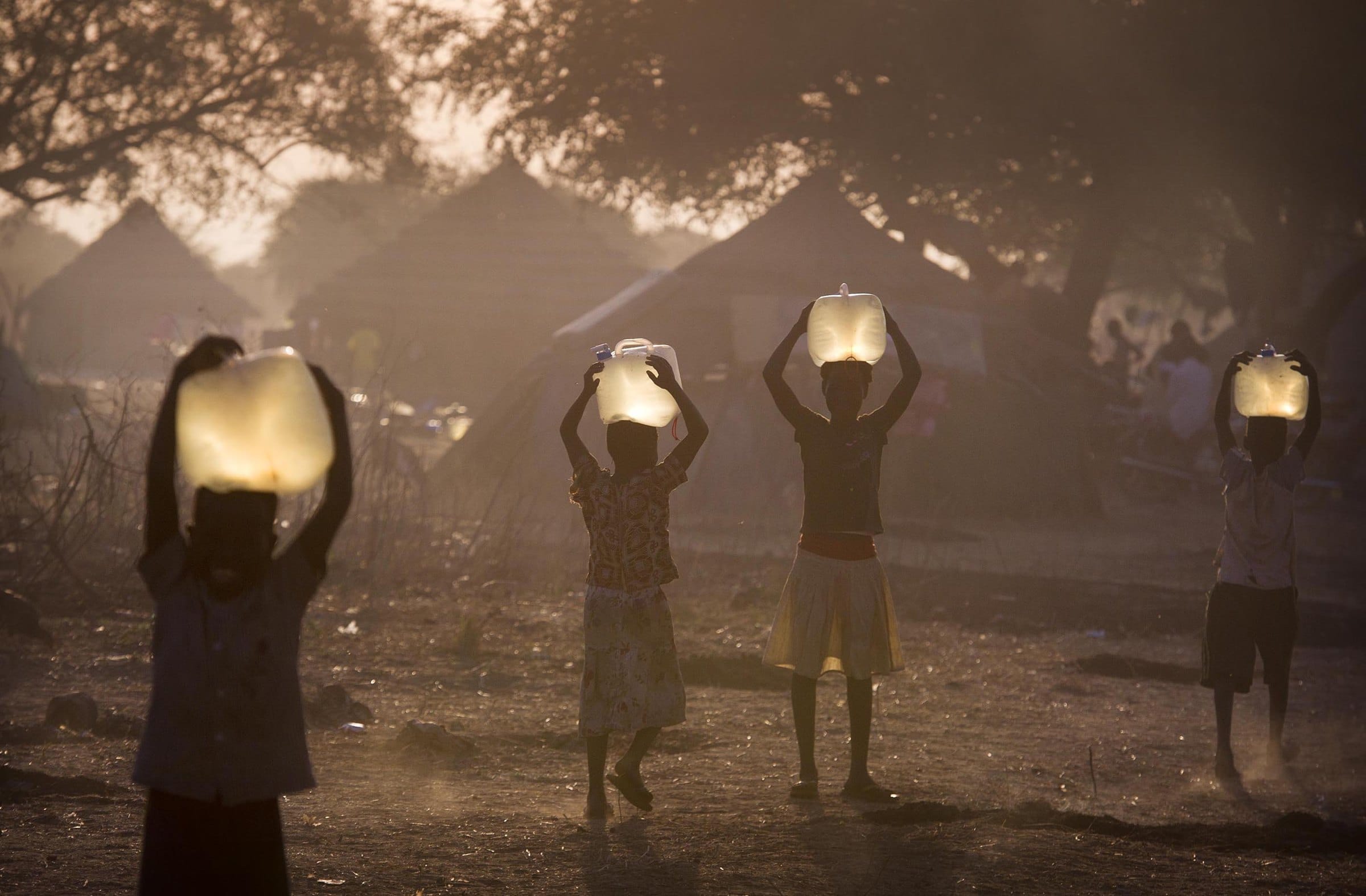 Children carry water home at dusk