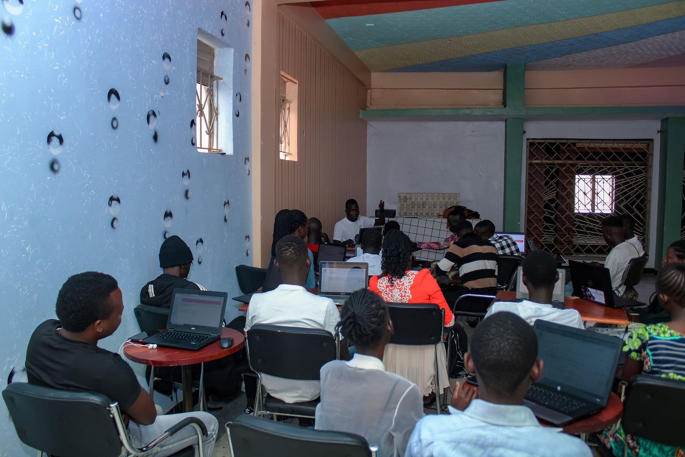 A full training room of young participants with laptops