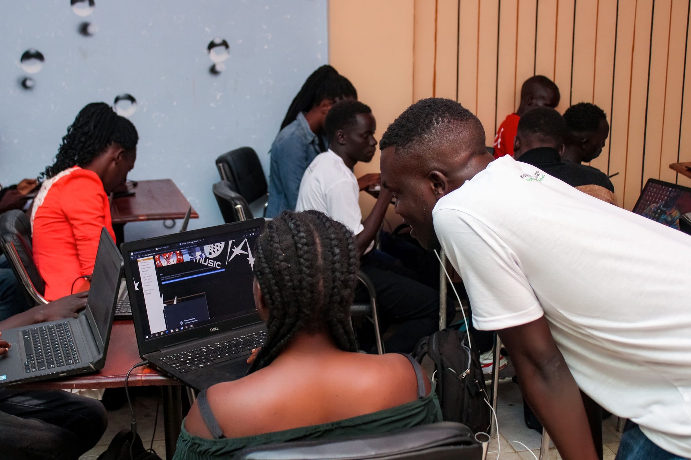 A facilitator helps a participant at a laptop during a training