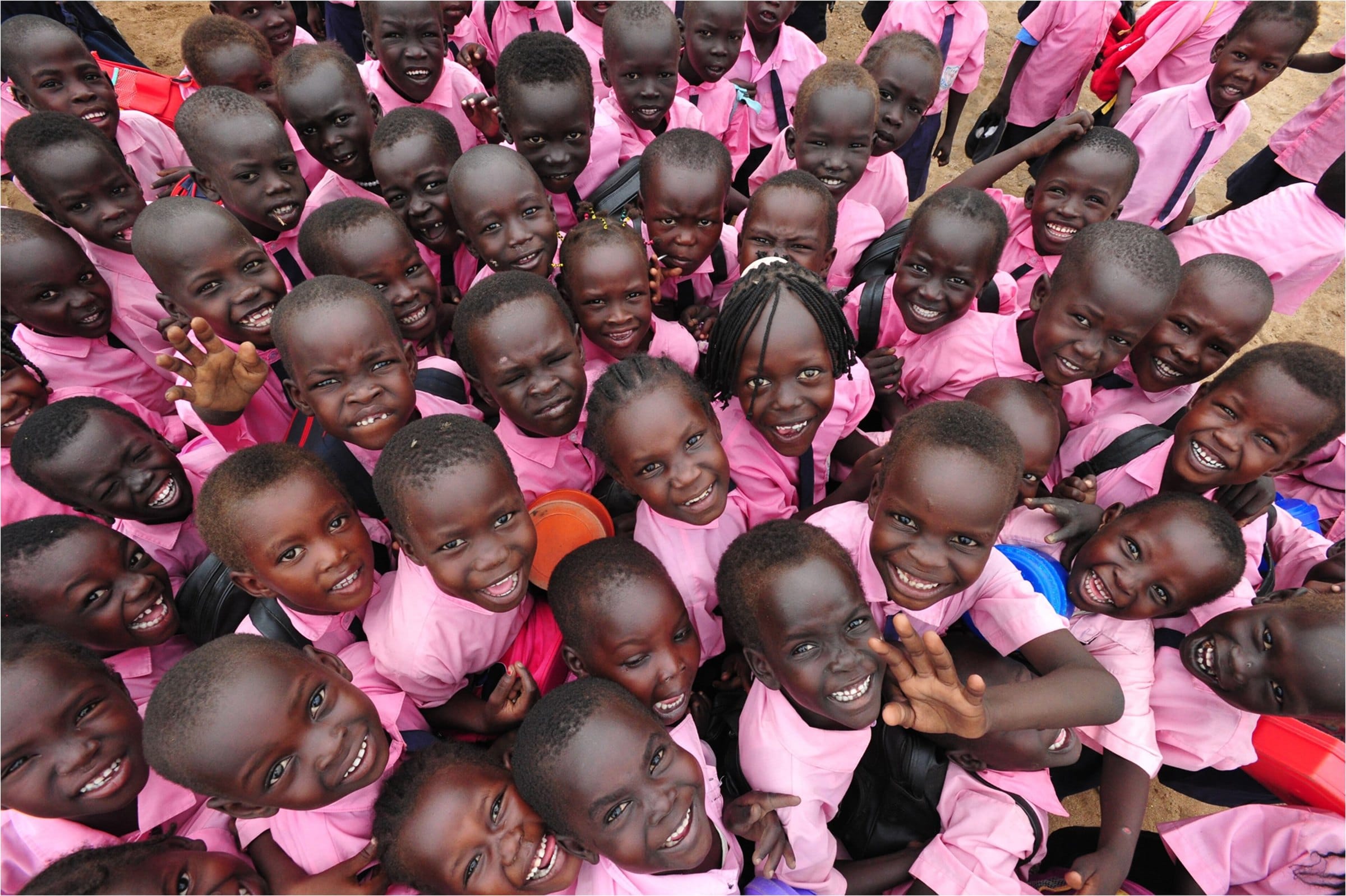 Smiling pupils in school uniform crowd together
