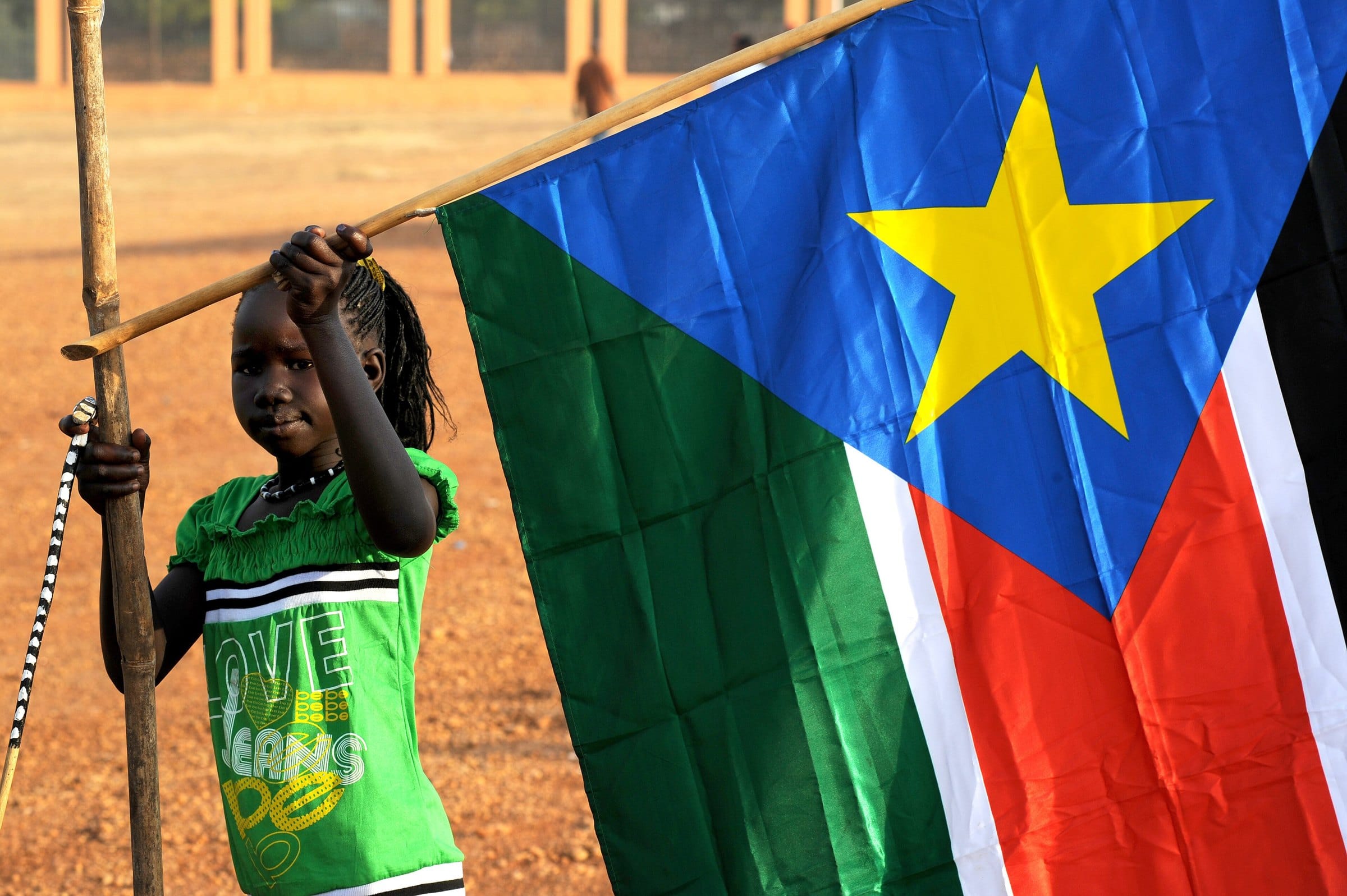 A young girl hangs up the flag of South Sudan