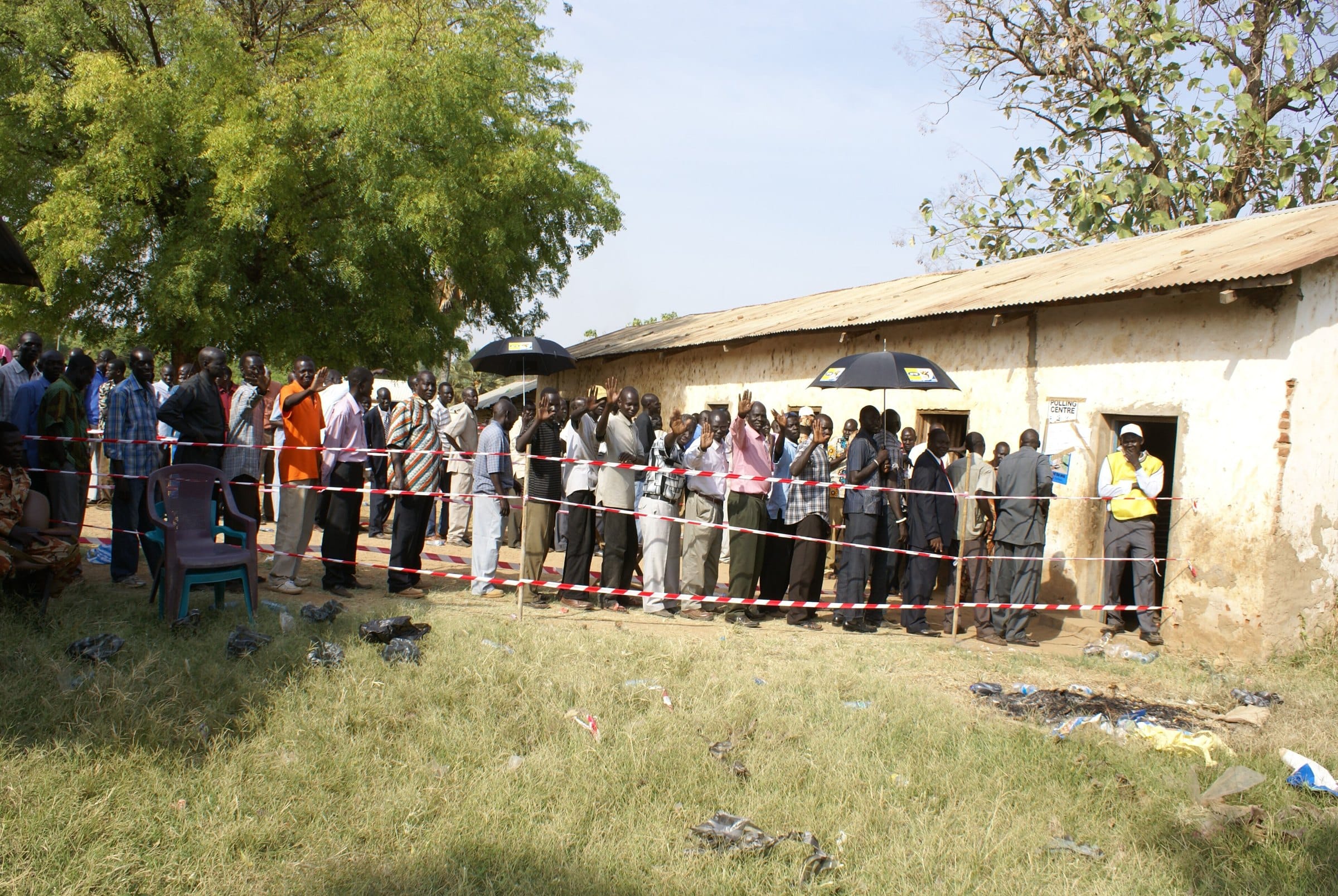 A long line of voters under the trees outside a polling station
