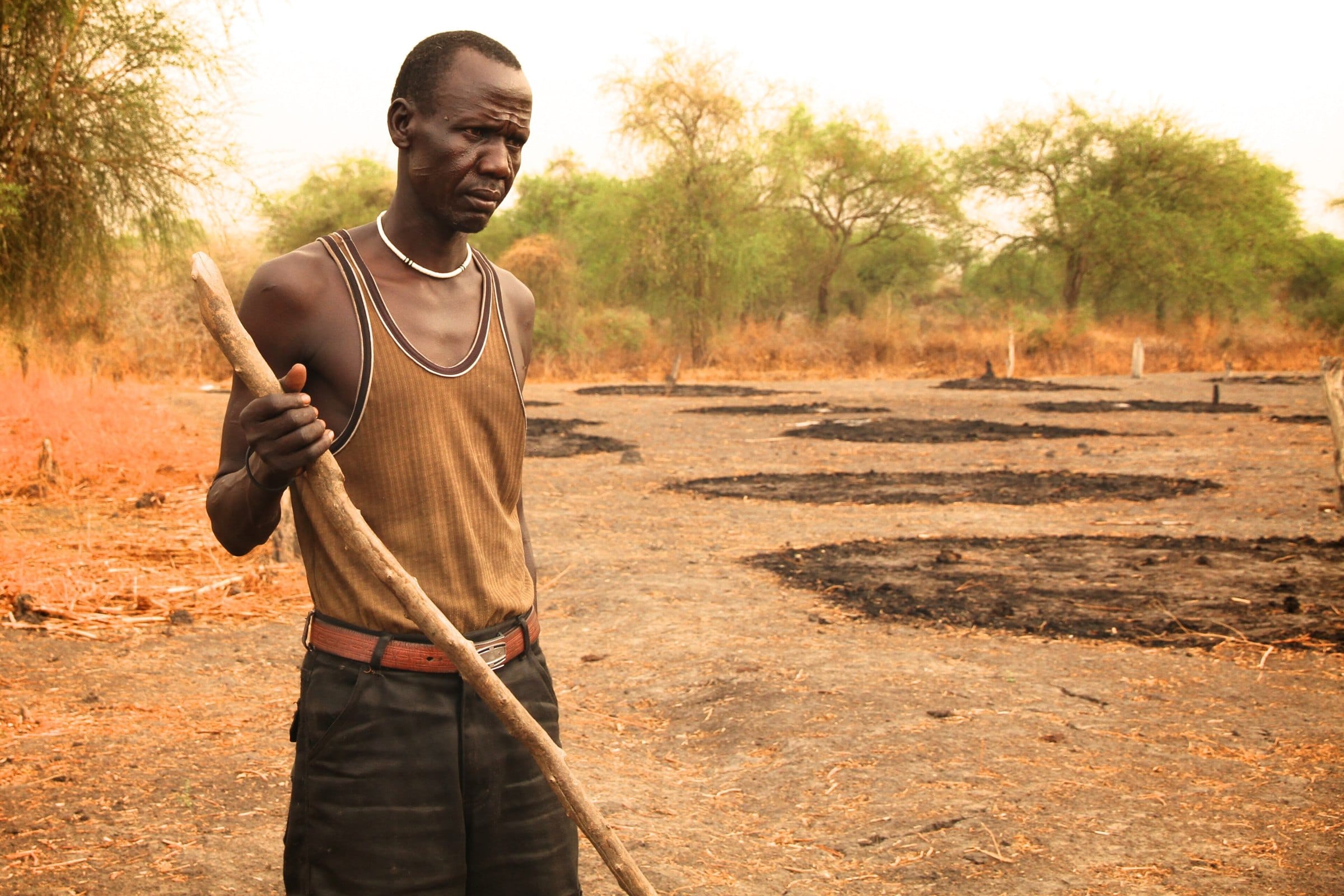 A farmer leans on his hoe in a cleared field