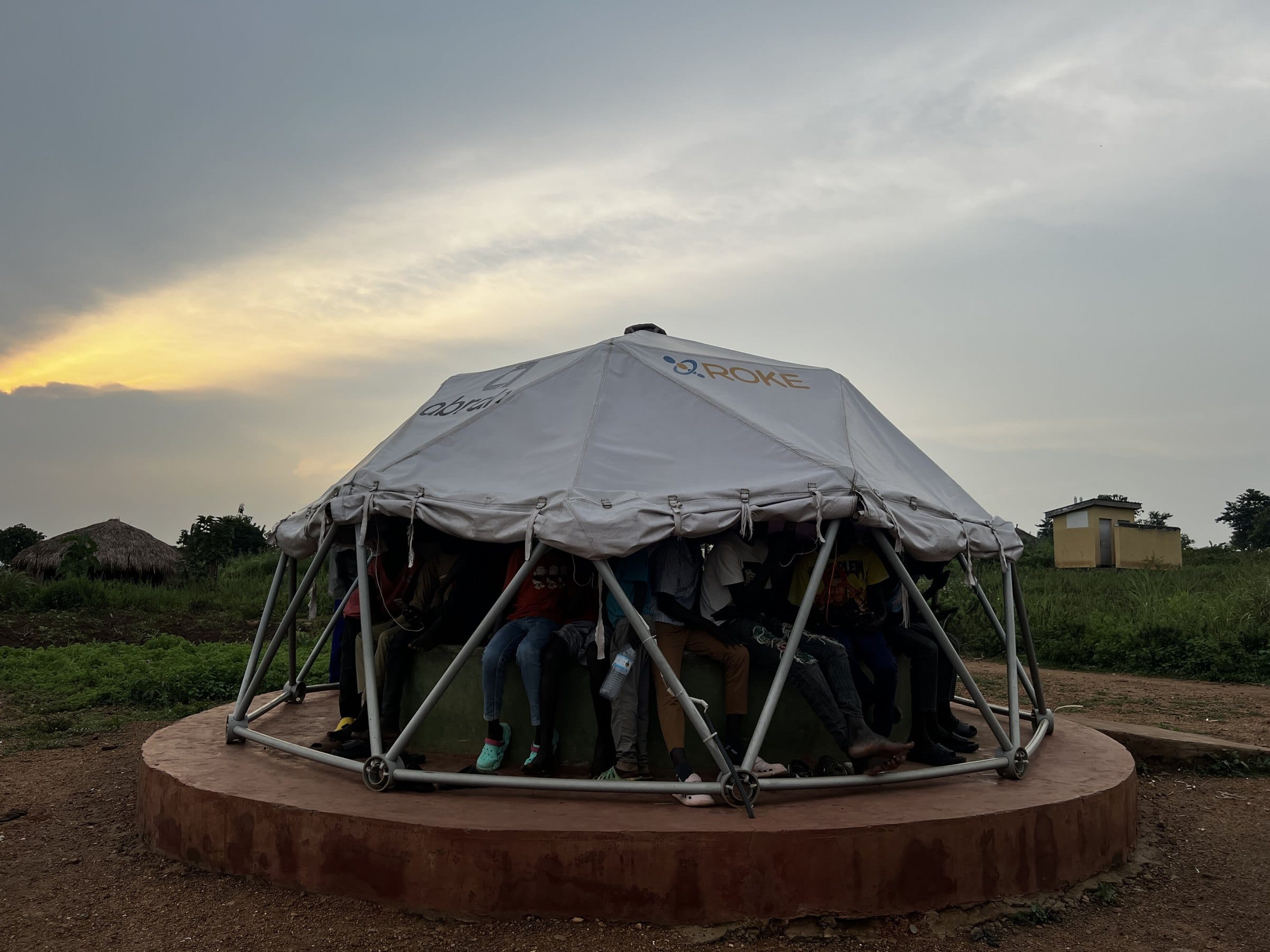 A domed community digital hub at dusk, with people working inside
