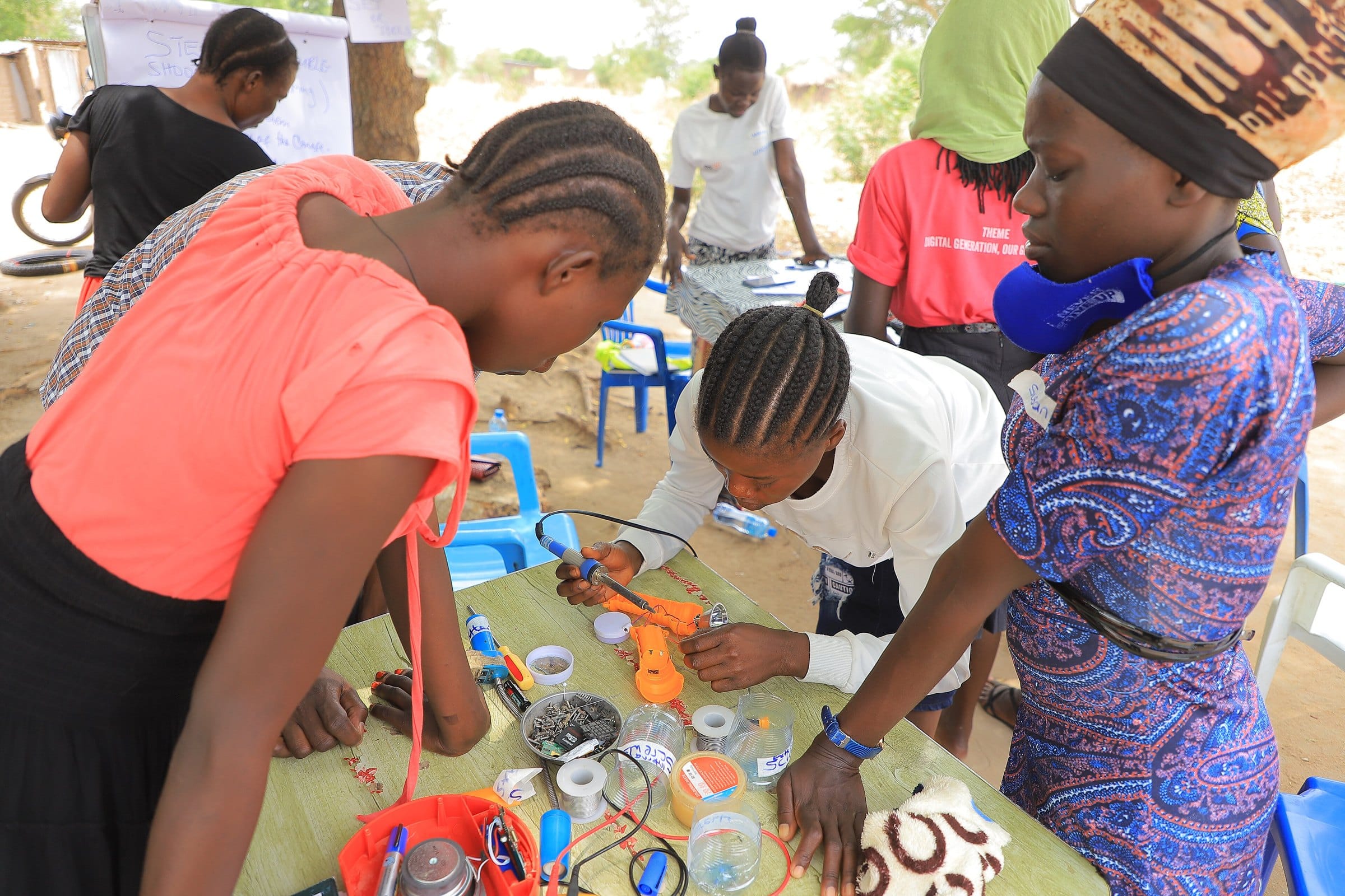 Women at a workbench repairing electronics in Rhino Camp