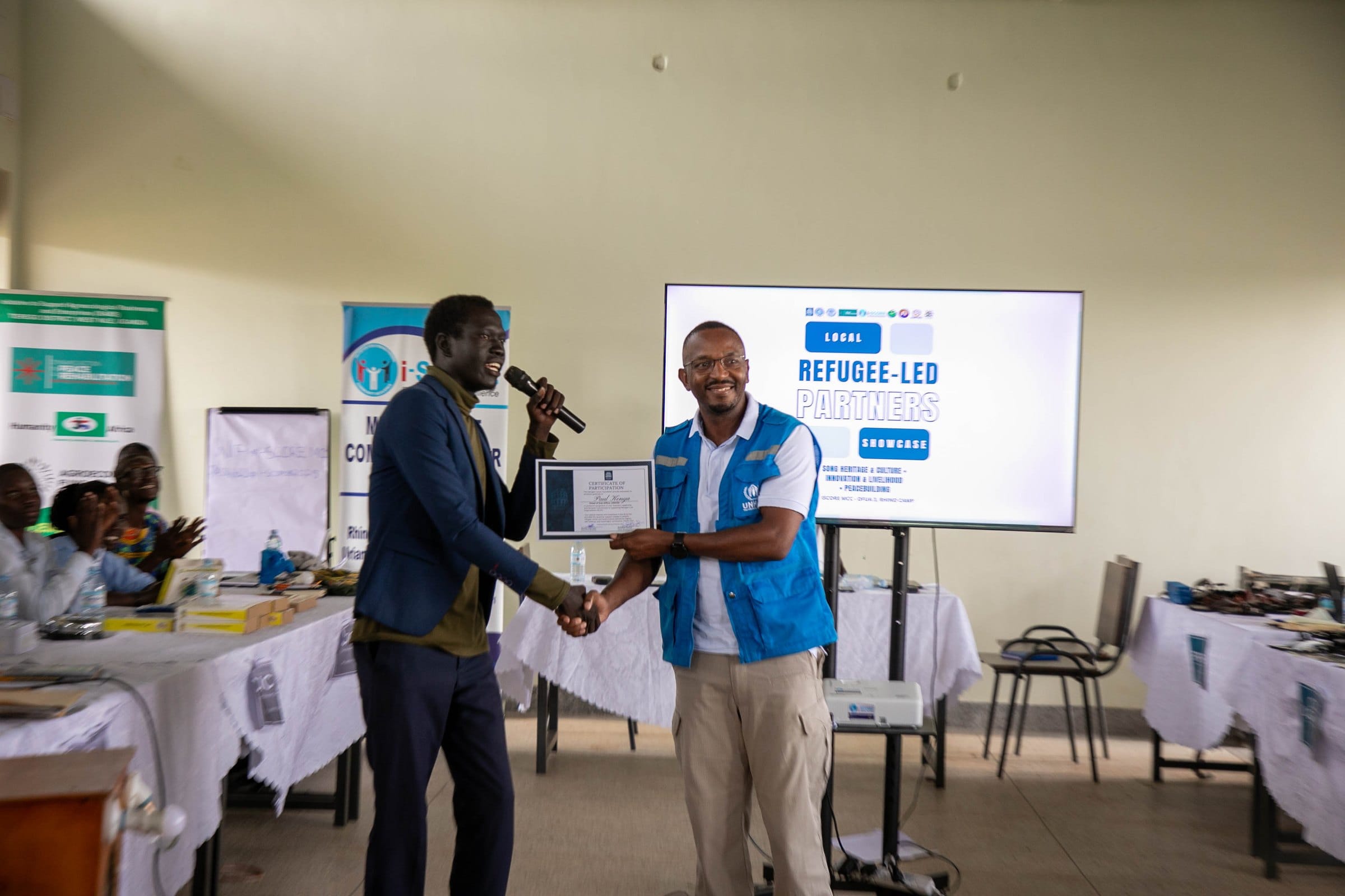 Ronald Ladu presenting a Certificate of Appreciation to Mr. Paul Kenya of UNHCR